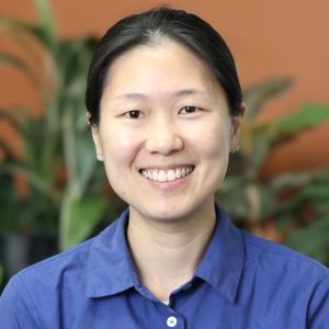 Image of speech pathologist, Kui Noi Tan, smiling warmly wearing a blue shirt emblazoned with the EduCare logo