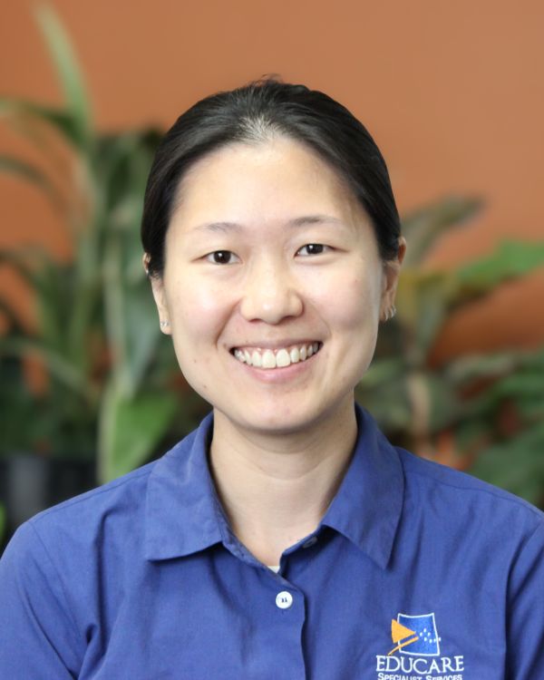 Image of speech pathologist, Kui Noi Tan, smiling warmly wearing a blue shirt emblazoned with the EduCare logo